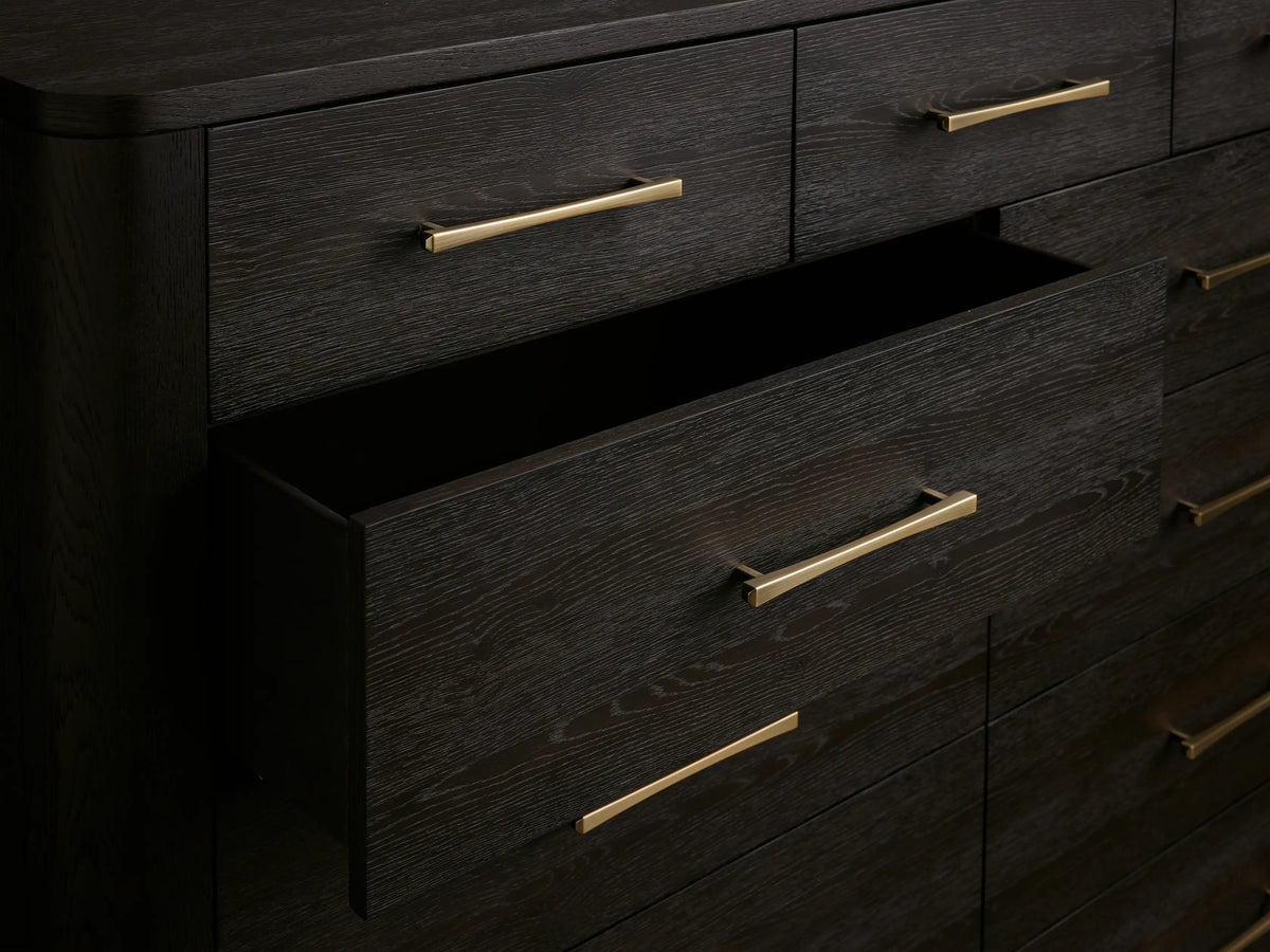 Calista Eleven-Drawer Dresser: dark oak, 3 top drawers, 8 lower, gold bar pulls, visible wood grain, on wood floor.