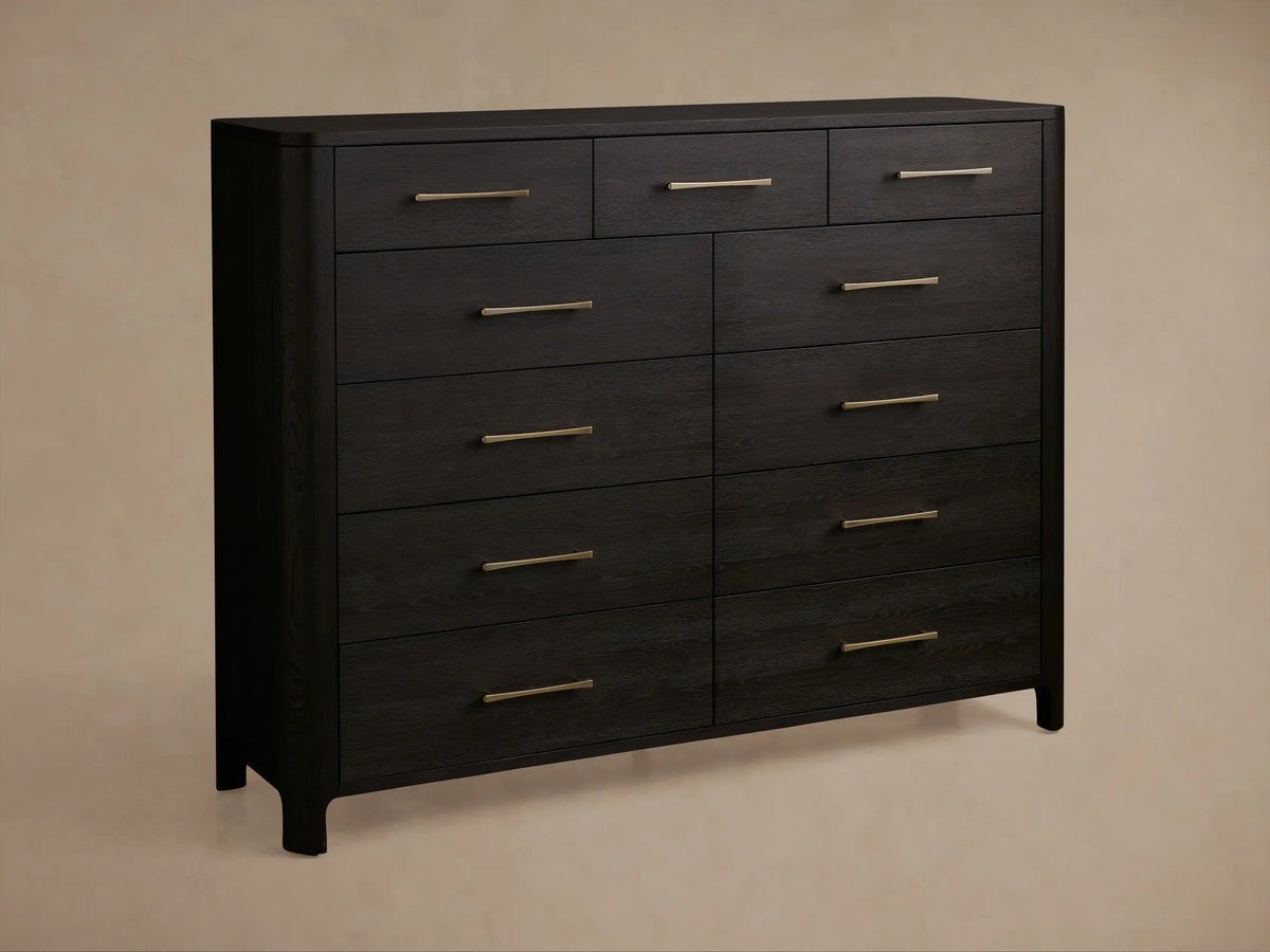 Calista Eleven-Drawer Dresser: Close-up of dark wood with prominent grain and brass bar handles. One drawer is partially open.