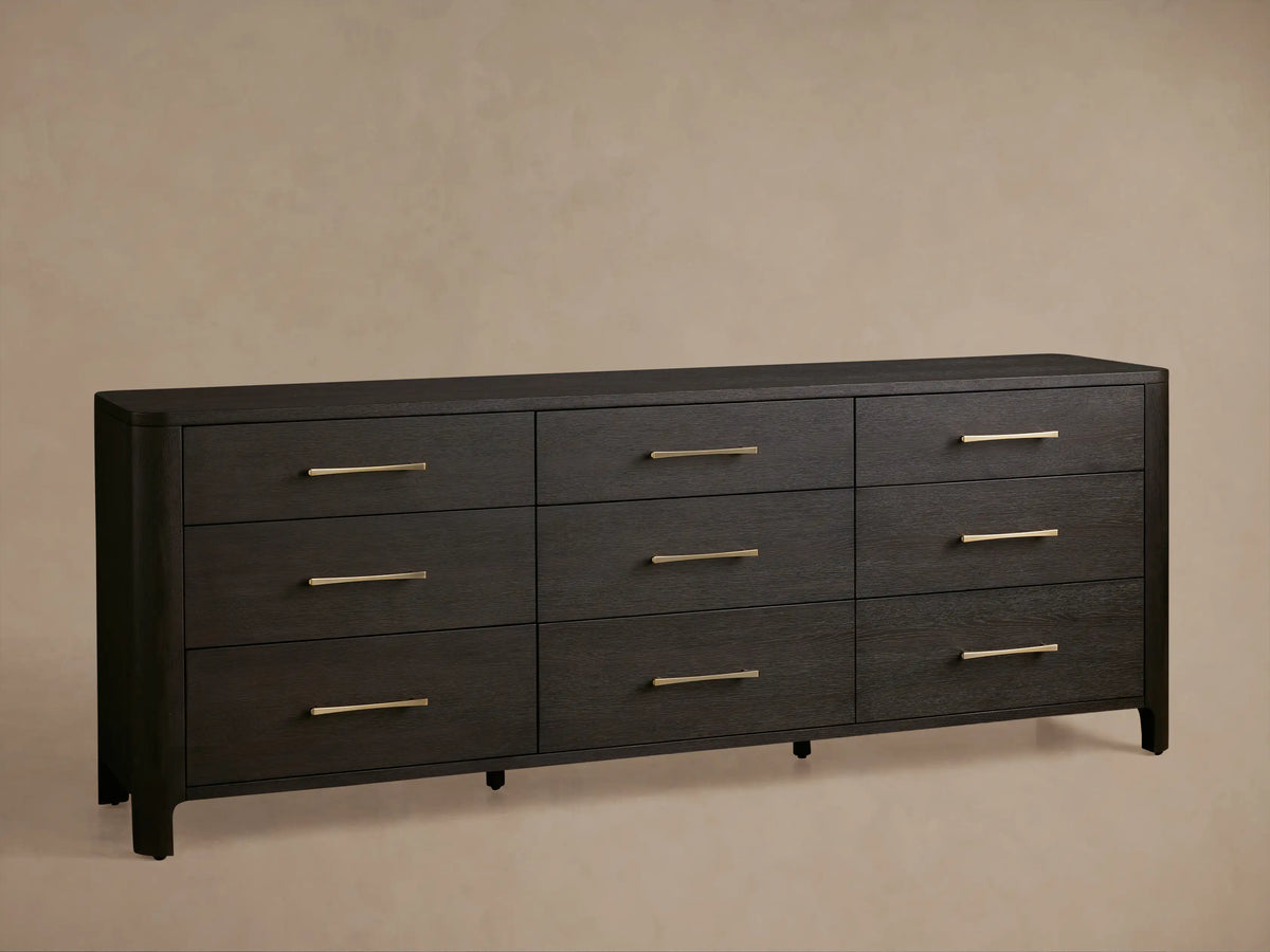 Dark espresso oak Calista dresser, visible grain, rounded corner. One drawer is partially open with a brass pull handle.