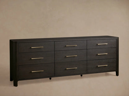 Dark espresso oak Calista dresser, visible grain, rounded corner. One drawer is partially open with a brass pull handle.
