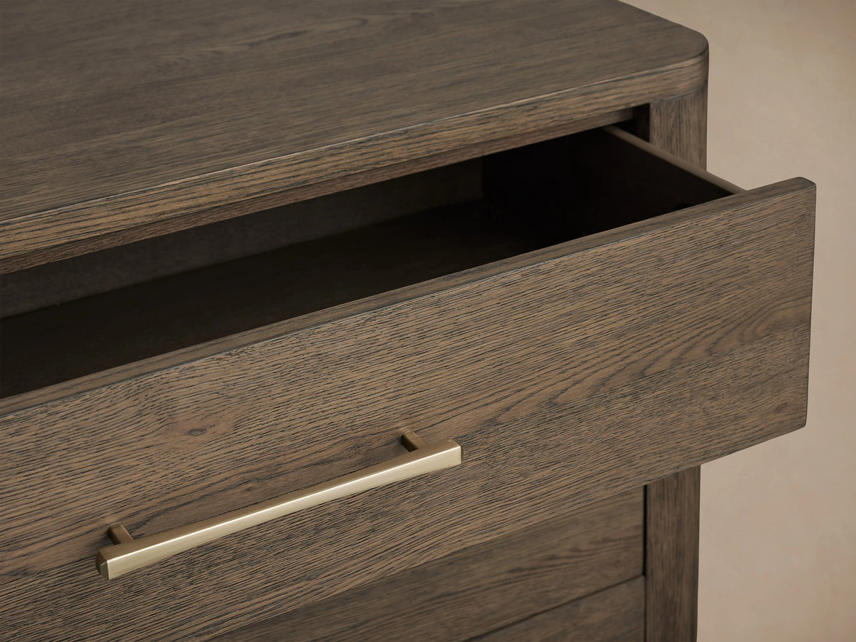 Calista Six-Drawer Dresser in veneered oak with a satin sheen finish, featuring a partially open drawer with gold handle.