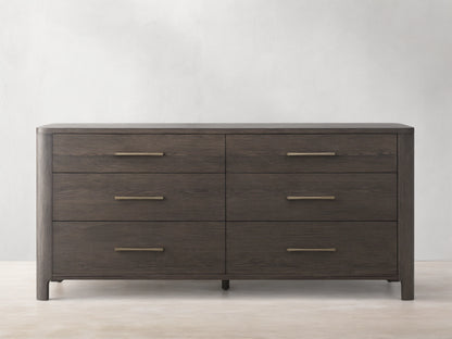Calista Six-Drawer Dresser in veneered oak with a satin finish, featuring sleek brass handles and wood grain texture.
