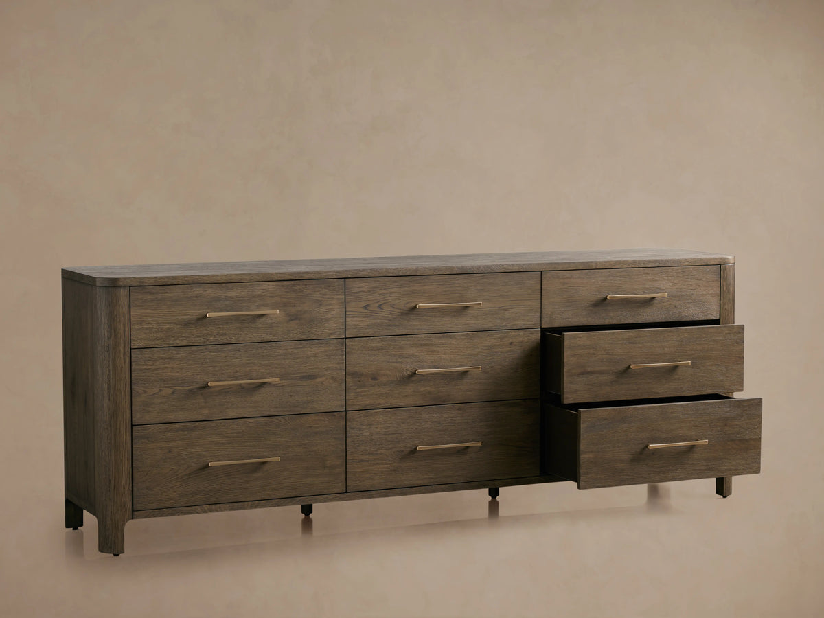 Calista Nine-Drawer Dresser in veneered oak with satin sheen. Three drawers partially open, showing complementing hardware.