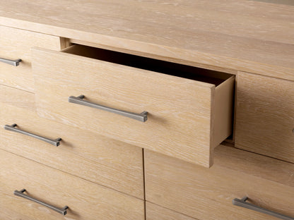 Calista Eleven-Drawer Dresser: Light oak veneer, rounded corners, 11 drawers. Two bottom right drawers open. Silver bar handles.