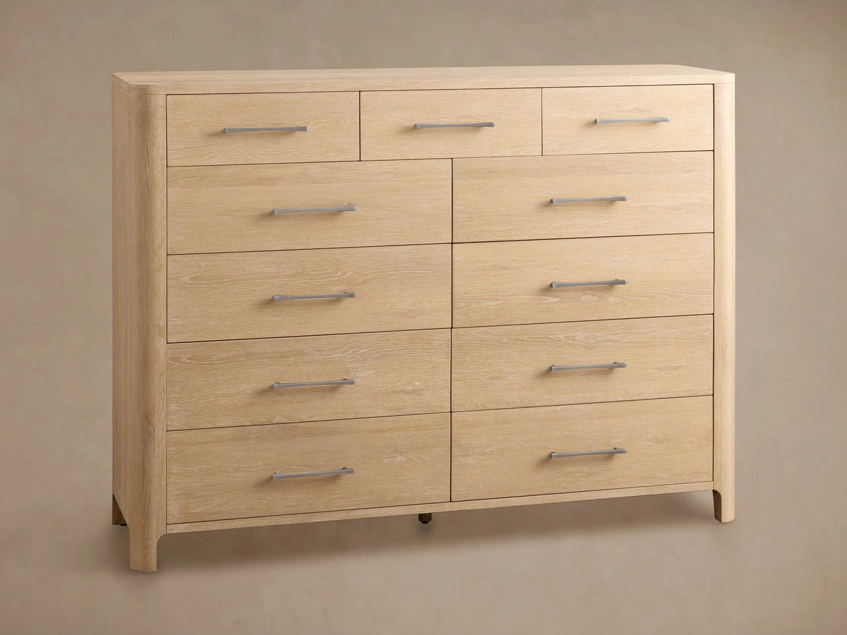 Calista Eleven-Drawer Dresser, light oak with visible grain. One drawer is open, revealing a dark interior; others show dark gray handles.
