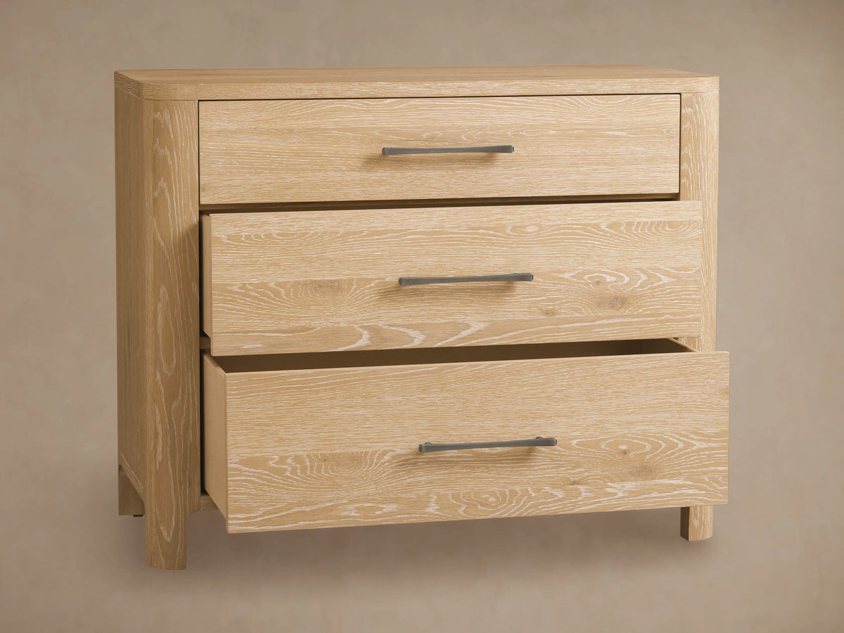 Calista Three-Drawer Chest made of light oak with natural wood grain, featuring three drawers and dark horizontal handles, against a wall.