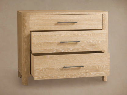 Calista Three-Drawer Chest made of light oak with natural wood grain, featuring three drawers and dark horizontal handles, against a wall.