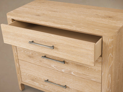 Calista Three-Drawer Chest, light oak wood with prominent grain. Top drawer closed, middle slightly open, bottom open; dark metal handles.