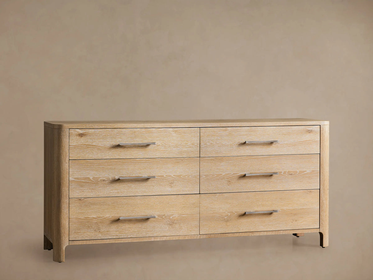 Calista Six-Drawer Dresser, light oak wood veneer. Angled view of top left, one drawer open showing gray interior, silver bar pulls.