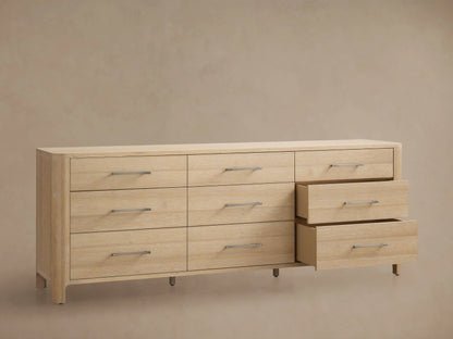 Calista Nine-Drawer Dresser: light oak wood with rounded edges. Features nine drawers with horizontal matte silver bar pulls. Front view.