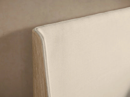 Front view of the Calista Bed with a cream upholstered headboard, light wood frame, and white bedding.