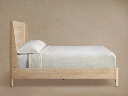CALISTA WOOD QUEEN BED SAND headboard with a light wood grain pattern, featuring a curved edge against a beige wall.