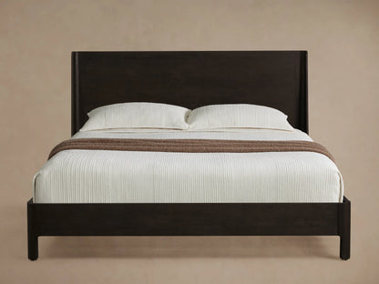 Calista Wood Bed: Dark oak frame with high, angled headboard. White textured bedding, 2 pillows, brown throw blanket on wood floor.