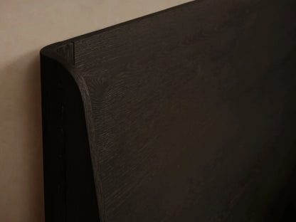 Calista Wood Bed with dark veneered oak frame, tall headboard, light cream ribbed bedding, and a brown throw blanket.