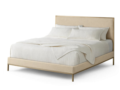 Beige Chamberlain Bed with upholstered headboard and frame, gold trim. White striped quilt and pillows on top.