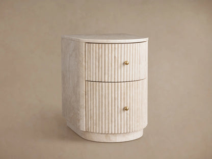 Close-up Clementine Reeded Stone Nightstand. Creamy stone with reeded texture, brass pulls. Bottom drawer partially open.