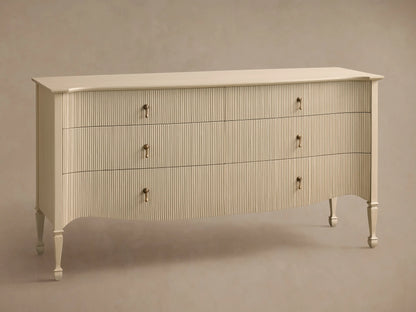 Conrad Six-Drawer Dresser, cream-colored with reeded texture, antique brass pendant pulls, elegant curved bottom, and tapered legs.