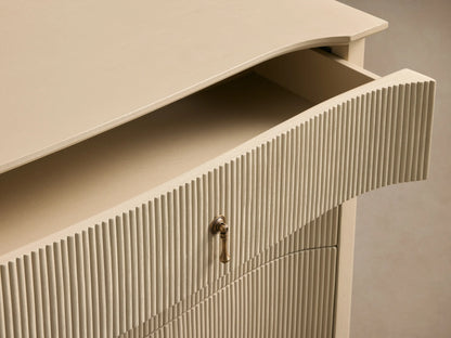 Conrad Six-Drawer Dresser, light cream, reeded facade on six drawers, with antique brass pendant pulls, curved base & tapered legs.