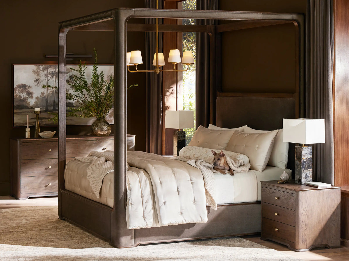 Conley Canopy Bed: dark oak wood frame, dark gray upholstered headboard & base, white bedding in a neutral room.