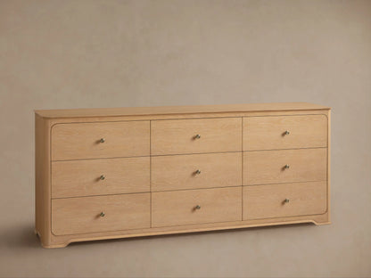 Conley Nine-Drawer Dresser: Light oak wood with 9 drawers, champagne brass pulls, rounded corners, subtle curved base.