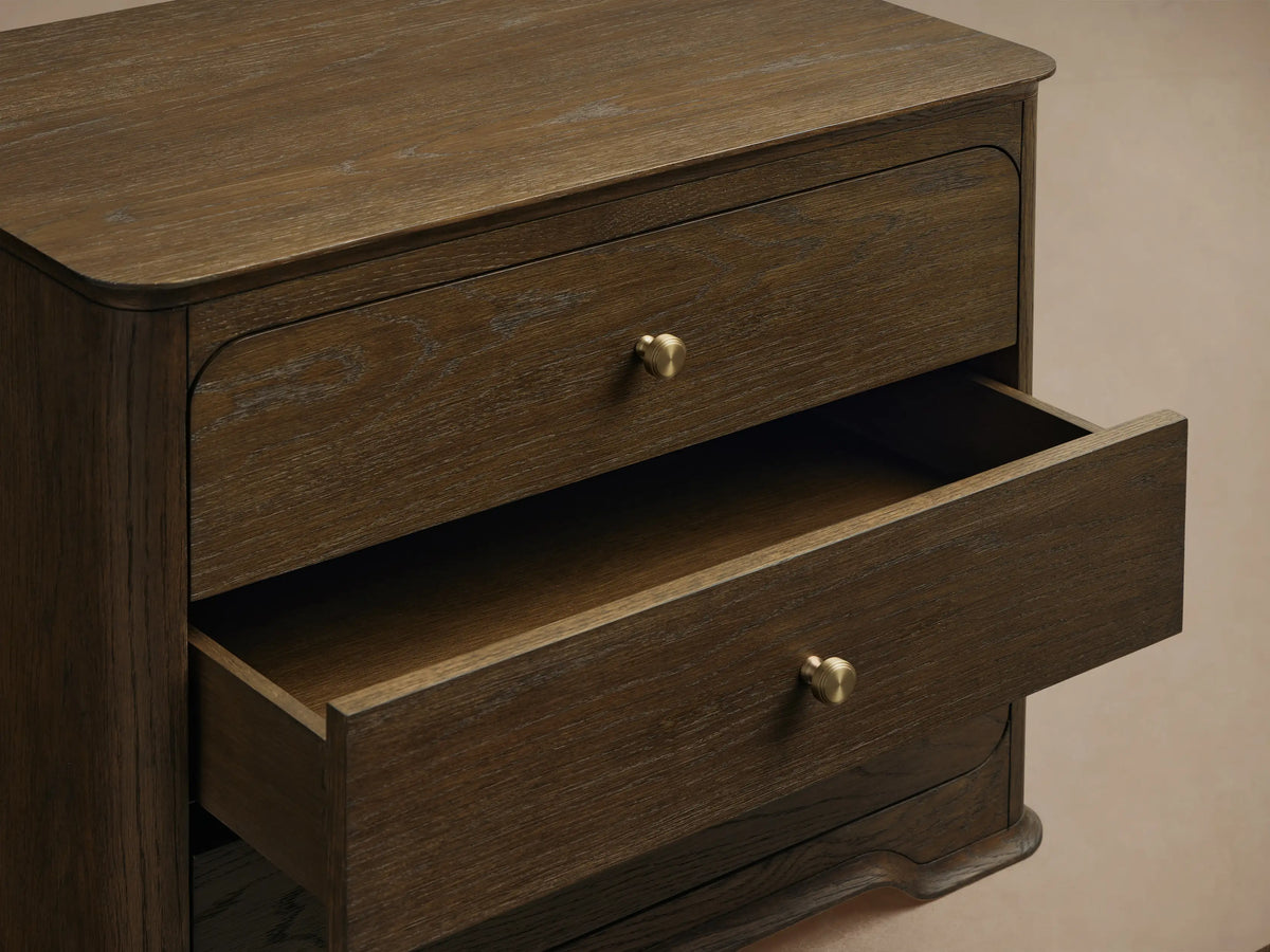 Dark brown oak Conley Nightstand, front view, with three drawers, round champagne brass pulls, and graceful curved edges and base.