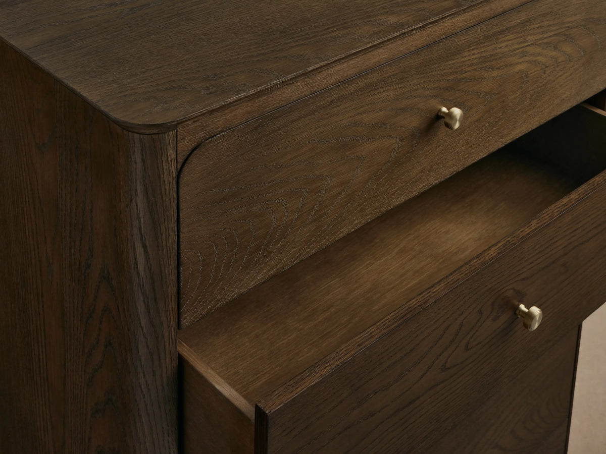 Conley Five-Drawer Dresser, dark brown oak, 5 stacked drawers with curved fronts and small champagne brass pulls, wood grain.