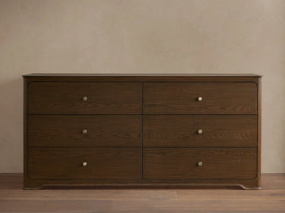 Conley Six-Drawer Dresser made of dark oak with visible wood grain, soft rounded edges & champagne brass knobs.