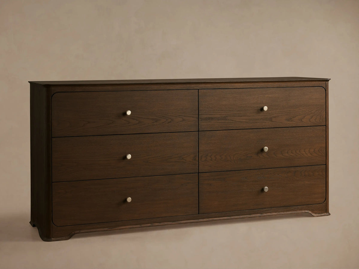 Front view of the Conley Six-Drawer Dresser, crafted from oak wood, showing graceful curvature and six drawers with champagne brass pulls.