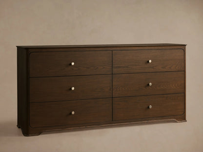 Front view of the Conley Six-Drawer Dresser, crafted from oak wood, showing graceful curvature and six drawers with champagne brass pulls.