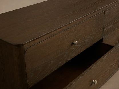 Conley Six-Drawer Dresser: Dark oak wood with six drawers, each having a champagne brass knob, and subtle curved edges.