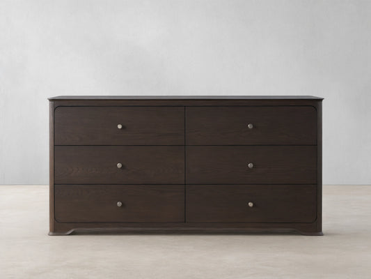 Conley Six-Drawer Dresser made of dark oak with visible wood grain, soft rounded edges & champagne brass knobs.