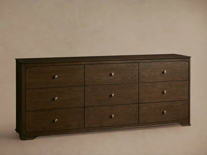 Conley Nine-Drawer Dresser: Dark brown oak wood, 9 drawers with visible grain and champagne brass pulls, against a beige wall.