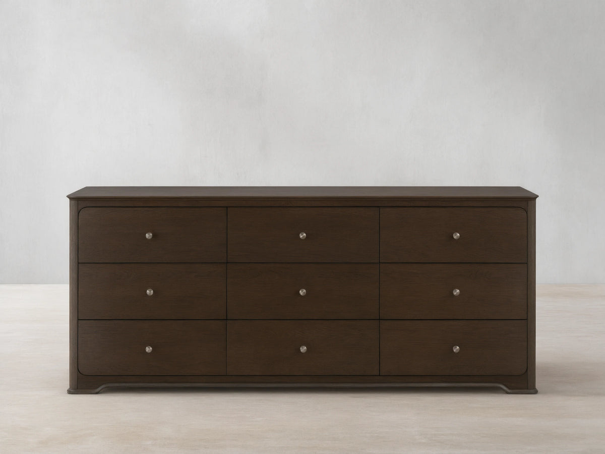 Conley Nine-Drawer Dresser: Dark brown oak wood, 9 drawers with visible grain and champagne brass pulls, against a beige wall.