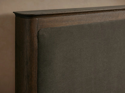 Conley Panel Bed with dark oak wood frame, dark upholstered headboard, and white quilted bedding, viewed front-on.