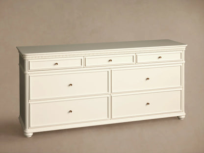Cr??me finished Carlisle dresser with fluted top molding, 7 drawers, and antique brass knobs on wood floor.