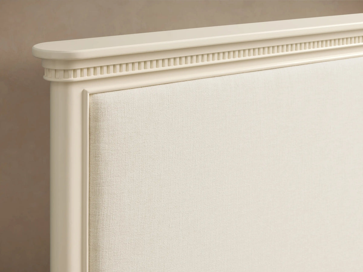 Full-view of a Carlisle Bed with a crv®me wood frame, upholstered headboard, and light ribbed bedding against a plain taupe wall.