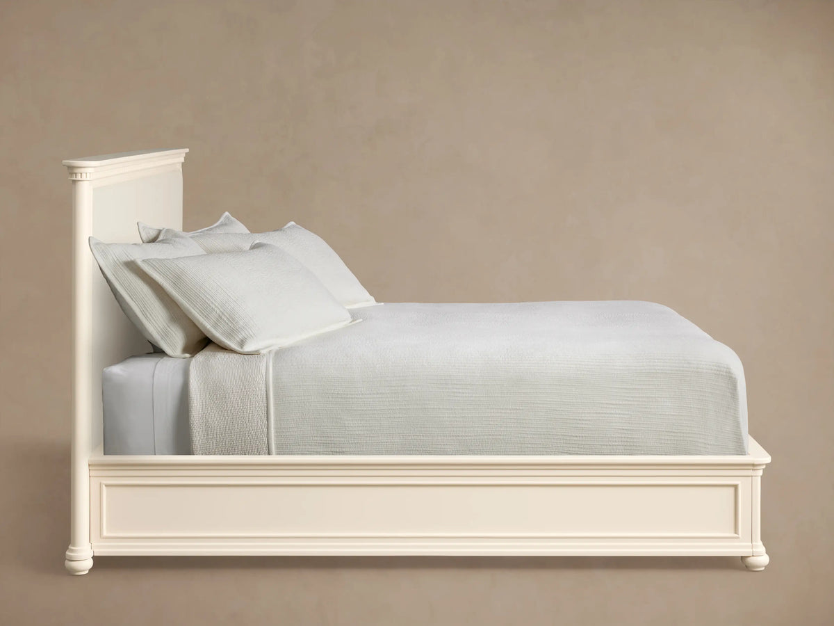 Close-up of Carlisle Bed headboard: Crv®me wood frame with fluted trim, bordering a textured off-white upholstered panel.
