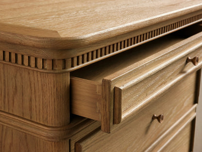 Carlisle Nightstand: Light oak wood with visible grain, 3 drawers, antique brass pulls, decorative trim, angled view.