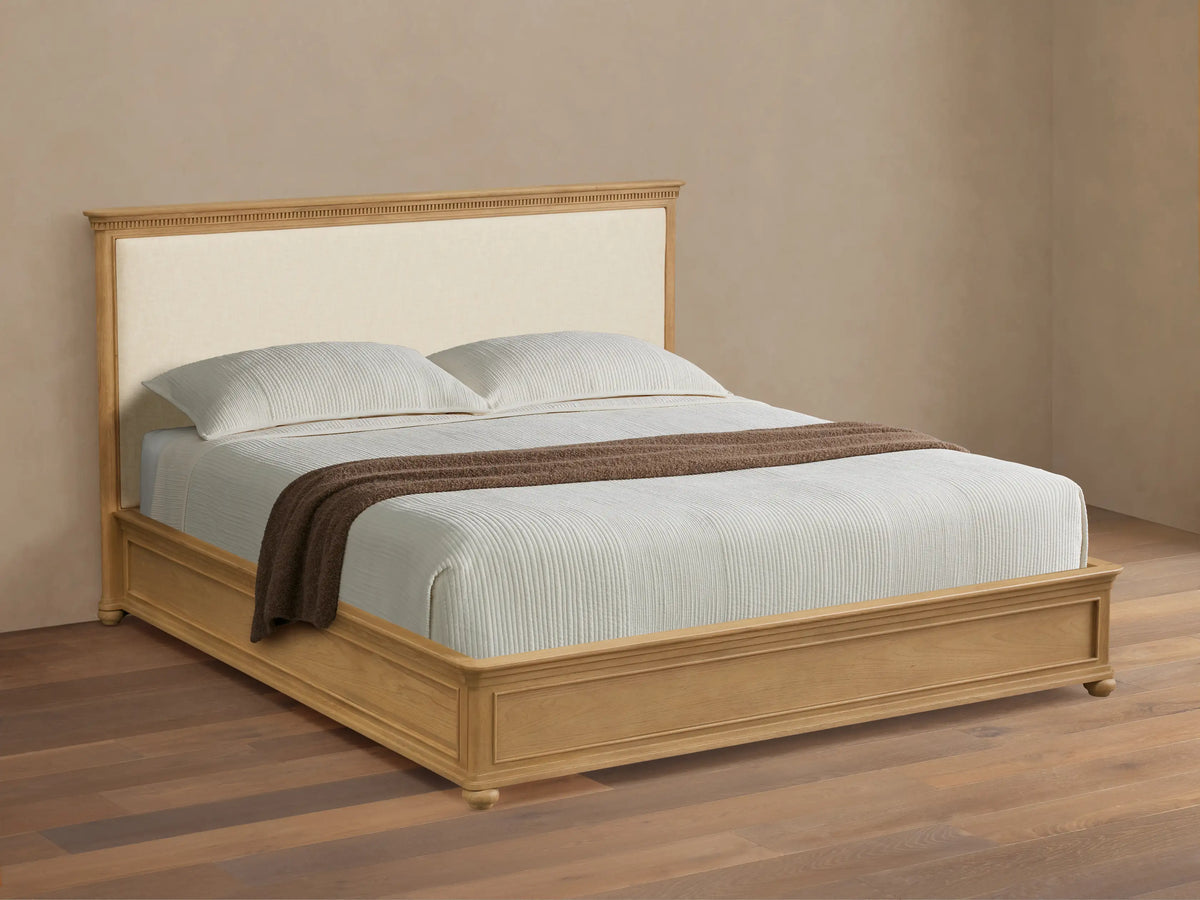 Carlisle Bed: Light oak frame, cream upholstered headboard, white striped bedding, brown throw, on wood floor.