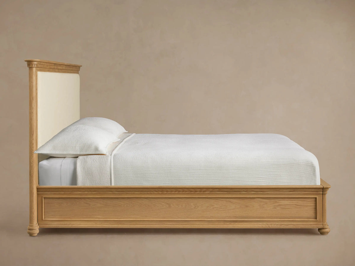 Close-up of Carlisle Bed's Marcona oak headboard, with carved details and Cr??me upholstered fabric.