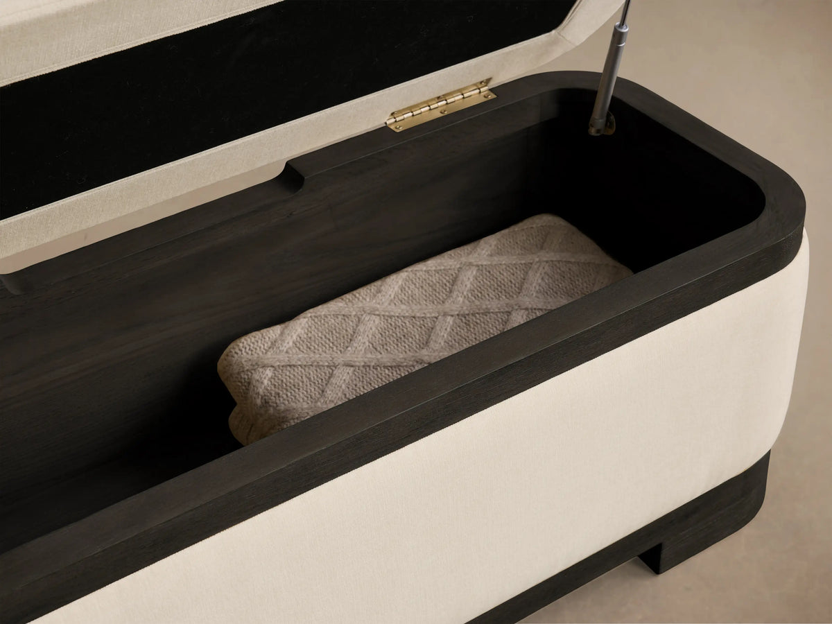 Front view of the Darien Curved Storage Bench, featuring a cream upholstered top and body with a dark brown base and trim.