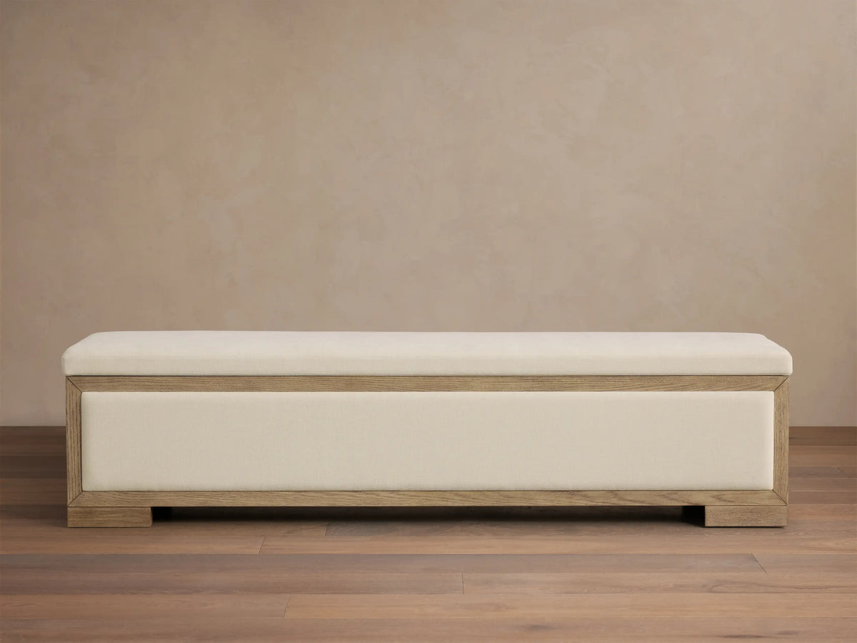 Front view of the Darien Storage Bench, featuring a light oak wood frame and cream upholstered top and front panel.