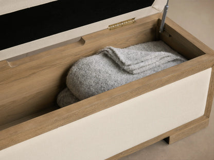 Front view of the cream Darien Storage Bench with light oak wood frame, upholstered top and side panels.