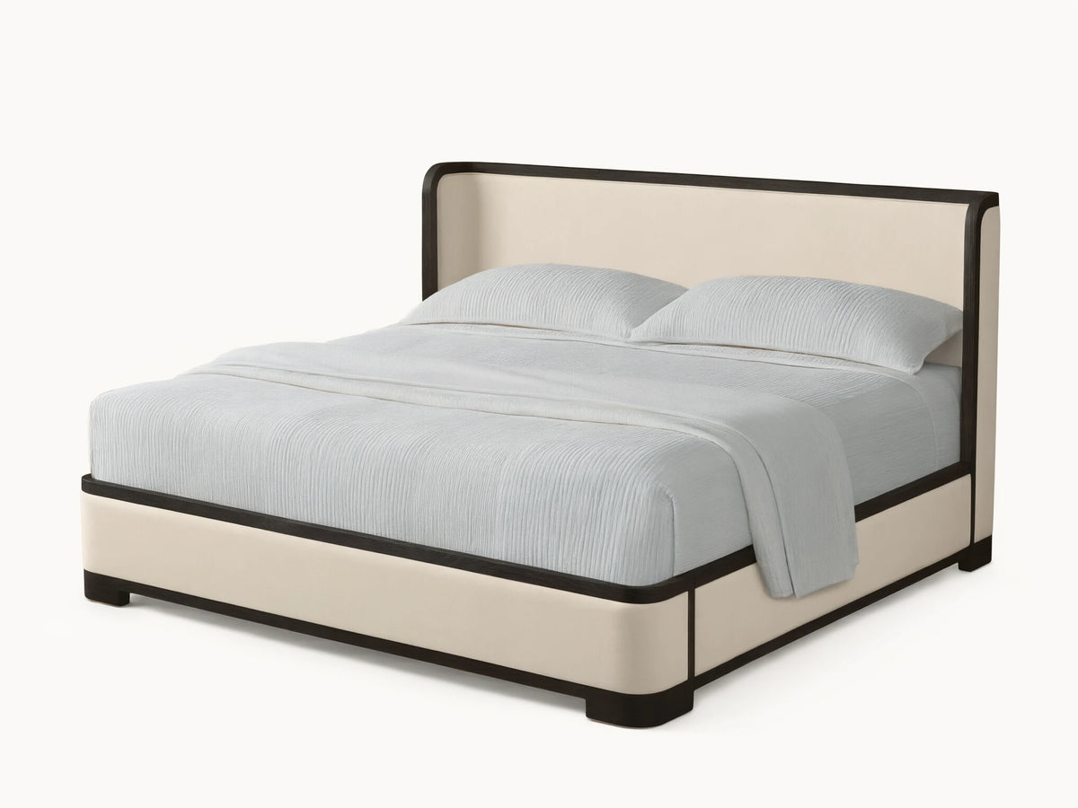 Darien Curved Shelter Bed, cream upholstered with dark frame, curved headboard & light ribbed bedding on a wood floor.