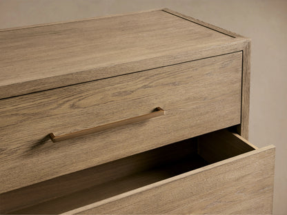 Darwyn Five-Drawer Dresser in oak wood, close-up of top drawer with brass pull, partially open below.