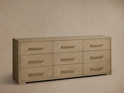 Front view of the light natural oak Darien Nine-Drawer Dresser with nine drawers and long brass-colored handles.