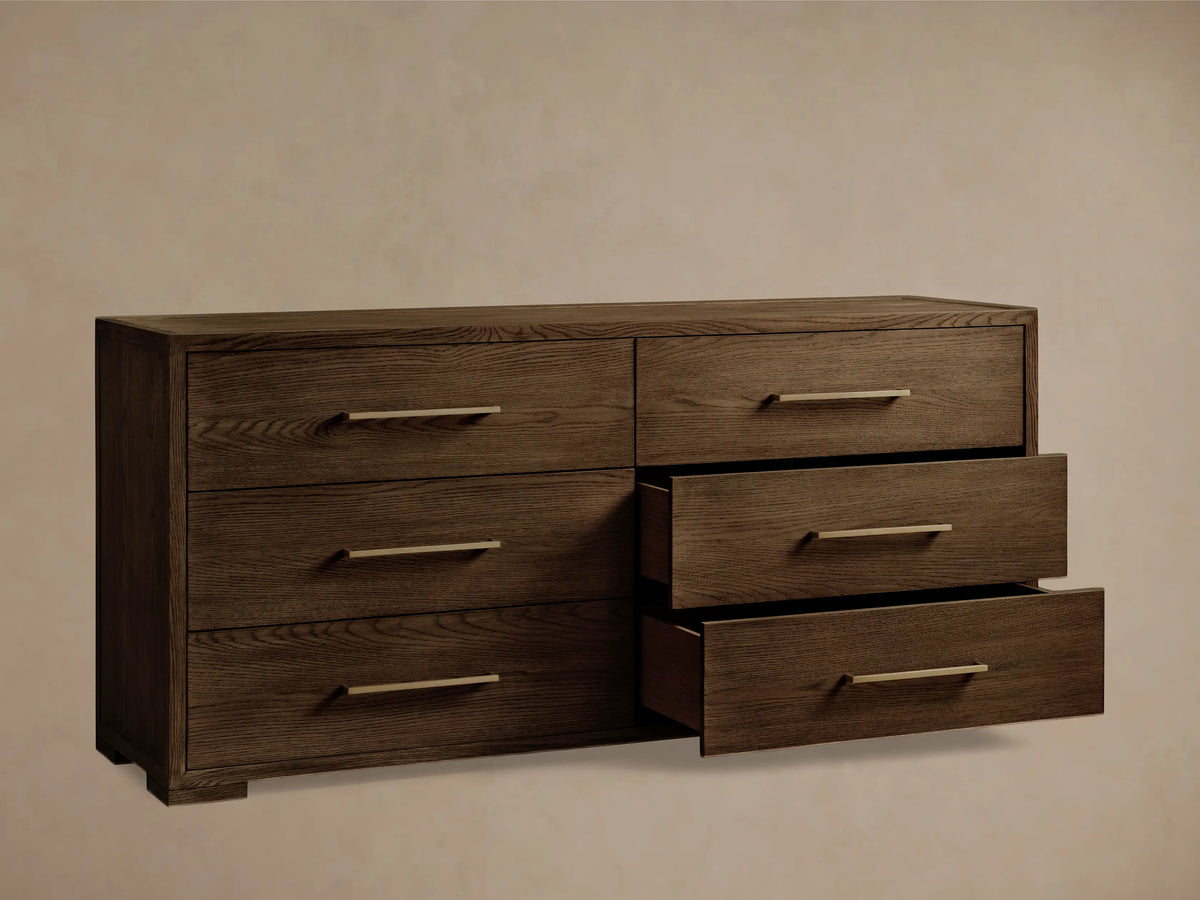 Angled close-up of the dark brown Darien Six-Drawer Dresser, showing rich wood grain, a brass drawer pull, and an open drawer.