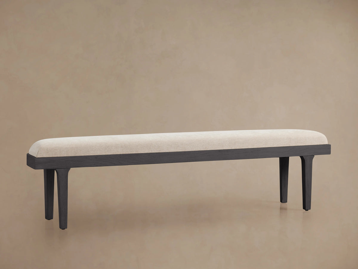 Danny Bench with a long, rectangular upholstered seat in light fabric atop a dark wooden frame with four legs.