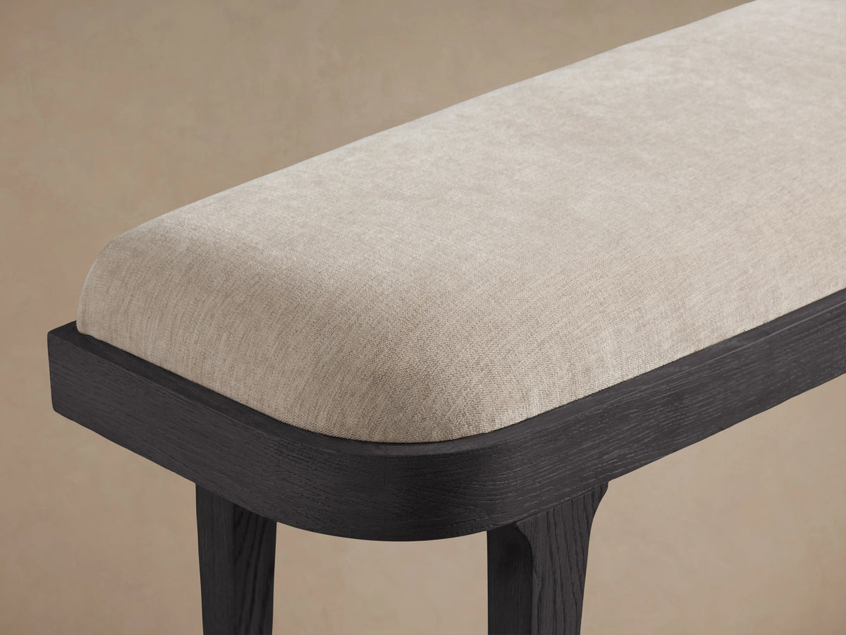 Danny Bench featuring an ebony-finished oak wood frame. The seat is upholstered in light fawn fabric with plush padding.