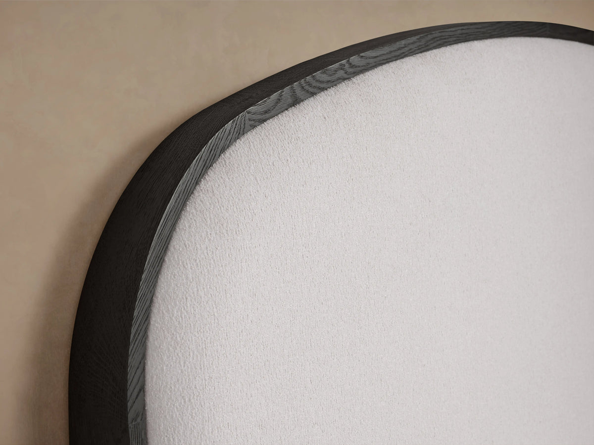 The image shows a close-up of the Danny Bed's headboard, featuring dark oak wood and white upholstered fabric with soft padding.
